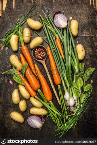 Fresh vegetables and herbs ingredients for cooking with old spoon on dark rustic wooden background, top view