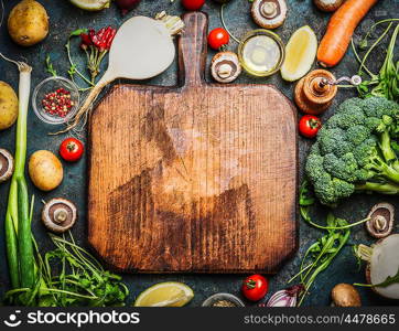 Fresh vegetables and ingredients for cooking around vintage cutting board on rustic background, top view, place for text. Vegan food , vegetarian and healthily cooking concept.