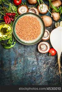 Fresh vegetables and ingredients with red lentil for healthy cooking on rustic background, top view, vertical border. Vegetarian food or diet eating concept.