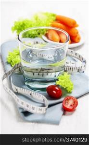 Fresh vegetables and measurement tape - diet and healthy eating concept - over white