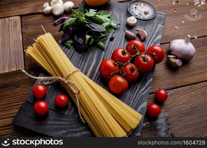 Fresh vegetables and spaghetti on wooden background. Organic vegetarian food, grocery assortment, natural products, healthy lifestyle concept. Fresh vegetables and spaghetti, wooden background