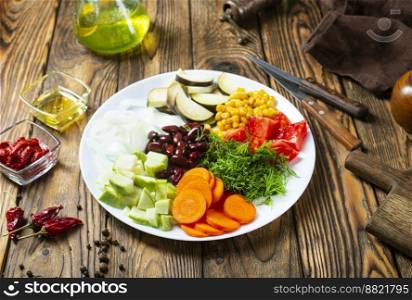 fresh vegetables: eggplants, beans, leek, tomatoes, chili peppers, carrot, garlic, onion on old wooden background, rustic style, top view