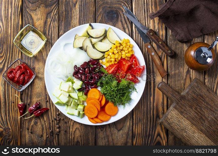 fresh vegetables  eggplants, beans, leek, tomatoes, chili peppers, carrot, garlic, onion on old wooden background, rustic style, top view