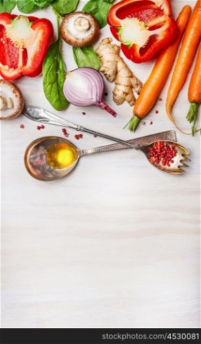 Fresh vegetables for Healthy cooking with spoons,oil and spices on light wooden background, top view. Vegan or clean diet food concept.