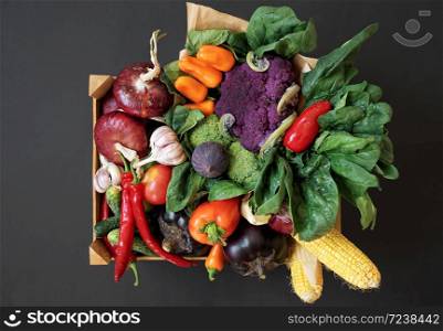 Fresh vegetables in a wooden box on a black background. Harvesting. Top view.