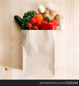 Fresh vegetables in paper bag on light wooden background. Food bag and eco-friendly concept. Healthy food background.
