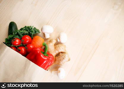 Fresh vegetables in paper bag on light wooden background. Food bag and eco-friendly concept. Healthy food background.