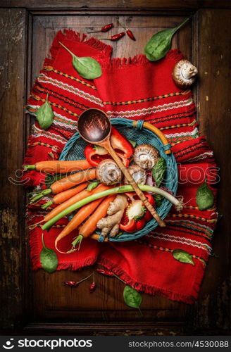 Fresh vegetables ingredients in basket with cooking spoon on rustic napkin. Vegetarian and healthy food concept. Top view