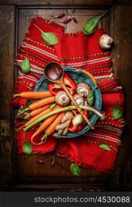 Fresh vegetables ingredients in basket with cooking spoon on rustic napkin. Vegetarian and healthy food concept. Top view