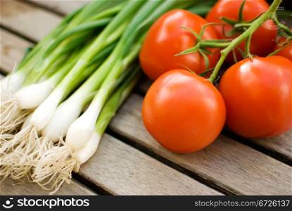 fresh vegetables tomatoes cucumber and green onion in basket over wooden table