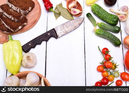 Fresh vegetables tomatoes, cucumber and pepper on a white wooden table, empty space in the middle