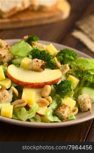 Fresh vegetarian salad with apple, lettuce, broccoli, cucumber, peanut, cheese and homemade croutons on plate, photographed with natural light (Selective Focus, Focus on the front of the apple slice)