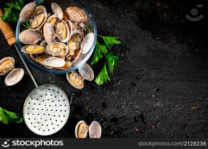 Fresh vongole in a glass bowl with parsley. On a black background. High quality photo. Fresh vongole in a glass bowl with parsley.