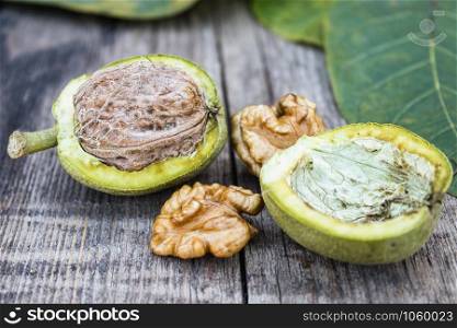 Fresh walnuts in a green shell near the walnut kernel on an old wooden table. Nuts in green shells. Harvest walnuts.. Fresh walnuts in a green shell near the walnut kernel on an old wooden table. Nuts in green shells.