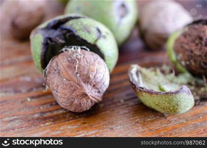 Fresh walnuts with green shells on a wooden surface. Walnuts, shelled and unshelled,close up.