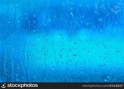 Fresh water on a blue window on a rainy day
