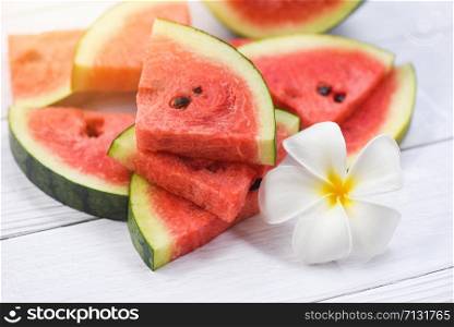 Fresh watermelon on wooden background / pile of red watermelon slices and white flower