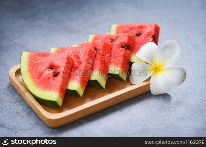 Fresh watermelon slice and white flower on black background