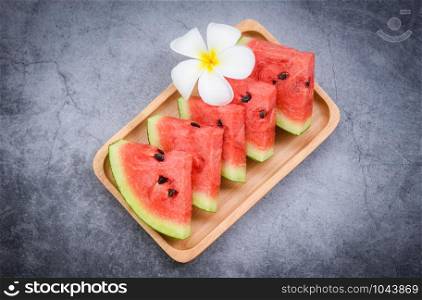 Fresh watermelon slice and white flower on black background / watermelon tropical fruit on wood tray , selective focus
