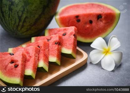 Fresh watermelon slice and white flower on the black background / watermelon tropical fruit on wood tray , selective focus