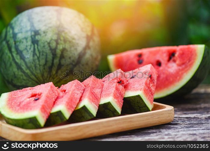 Fresh watermelon slice on wooden plate / Fruit of watermelon half on nature green background
