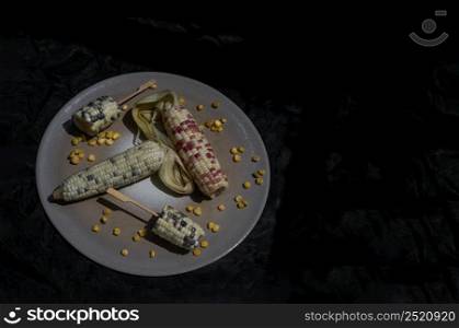 Fresh waxy corn or Sweet glutinous corn and Corn kernels over Round ceramic tray on Dark background. Tropical whole grain food, Copy space, Selective focus.