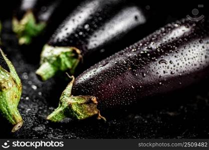 Fresh wet eggplant on the table. On a black background. High quality photo. Fresh wet eggplant on the table. 