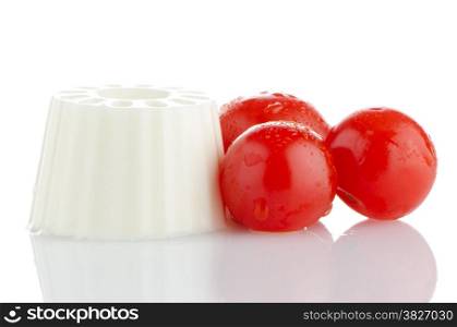 Fresh white cheese and cherry tomatoes on white reflective background.