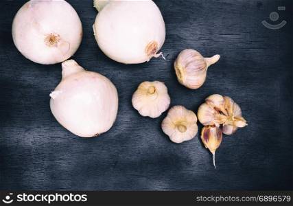 fresh white onion and garlic fruits on a black background, top view