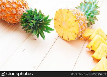 Fresh whole and cut pineapples on wooden background