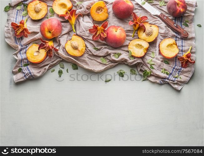 Fresh whole and halves peach with garden flowers and knife on light background, top view