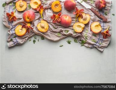 Fresh whole and halves peach with garden flowers and knife on light background, top view