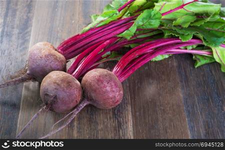 Fresh whole beetroots with leaves on wooden rustic table.Whole beetroots