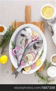 Fresh whole dorada fish and ingredients for cooking. Raw sea bream with spices on white background. Healthy food, diet. Top view with copy space.