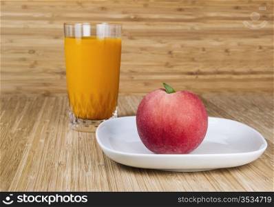 Fresh whole peach with peach drink and bamboo in background