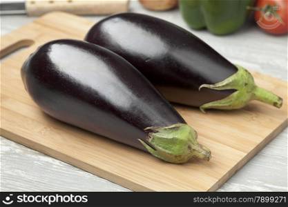 Fresh whole purple eggplants on a cutting board