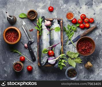 Fresh whole raw trout on a kitchen board.Fresh fish with vegetables and seasonings.. Raw salmon and ingredients