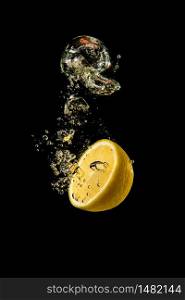 Fresh yellow lemon half in water splash on black background with lots of air bubbles. Refreshment concept. Fresh yellow lemon half in water splash on black background with lots of air bubbles.