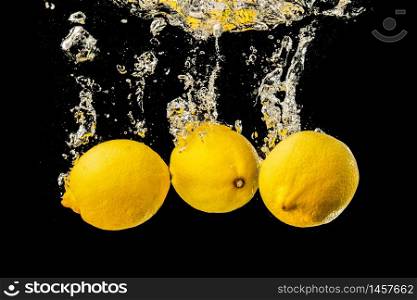 Fresh yellow lemons in water splash on black background with lots of air bubbles. Refreshment concept. Fresh yellow lemons in water splash on black background with lots of air bubbles.