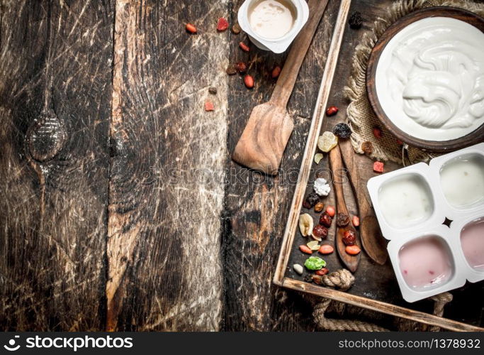 Fresh yoghurt with dried fruits on a tray. On a wooden background.. Fresh yoghurt with dried fruits on a tray.