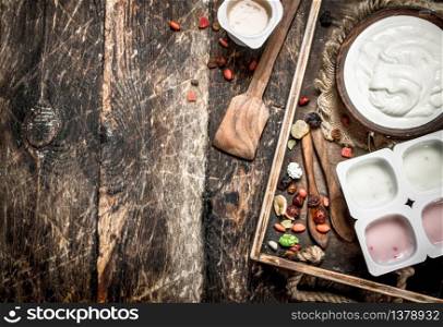 Fresh yoghurt with dried fruits on a tray. On a wooden background.. Fresh yoghurt with dried fruits on a tray.