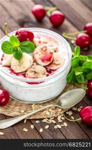 Fresh yogurt with cherry, banana and oats, delicious dessert for healthy breakfast