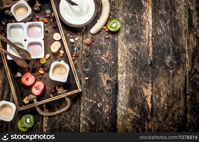 Fresh yogurts with fruits and nuts. On a wooden background.. Fresh yogurts with fruits and nuts.