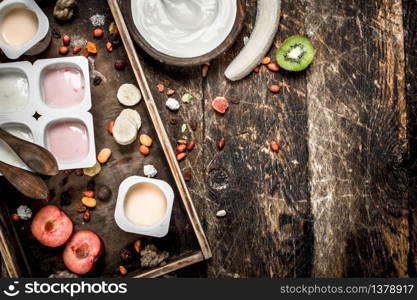 Fresh yogurts with fruits and nuts. On a wooden background.. Fresh yogurts with fruits and nuts.