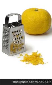 Fresh zest of a yellow Japanese Yuzu and grater on white background