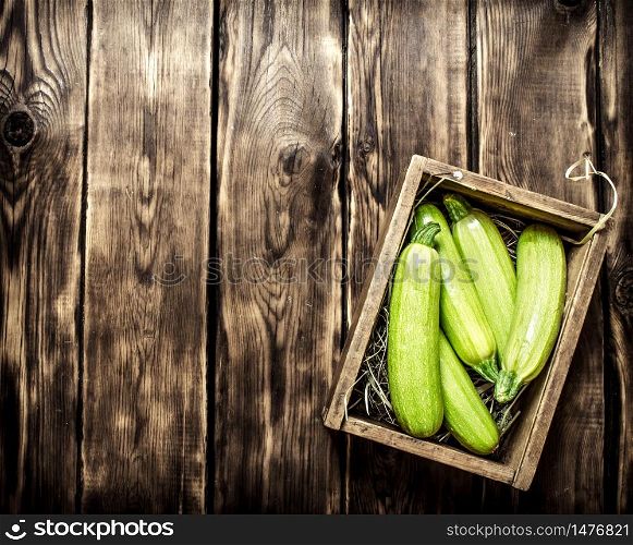 Fresh zucchini in an old box. On wooden background.. Fresh zucchini in an old box.