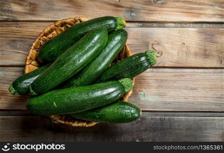 Fresh zucchini in the basket. On wooden background. Fresh zucchini in the basket.