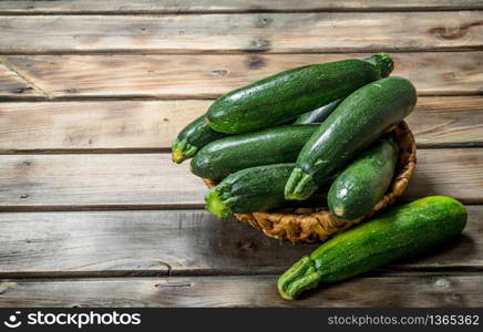 Fresh zucchini in the basket. On wooden background. Fresh zucchini in the basket.