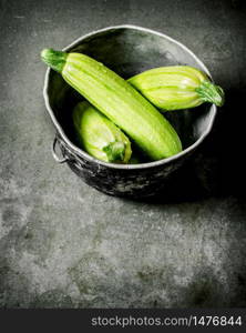 Fresh zucchini in the old pot. On a stone background.. Fresh zucchini in the old pot.