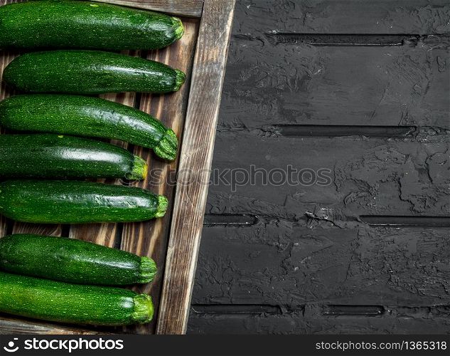 Fresh zucchini on tray. On black rustic background. Fresh zucchini on tray.